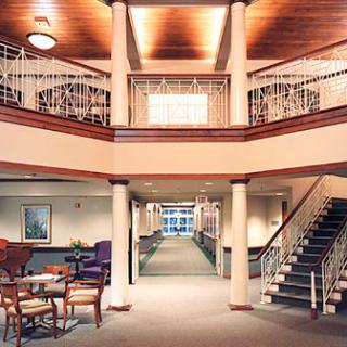 A spacious hotel lobby featuring elegant columns, a seating area, and grand staircase.
