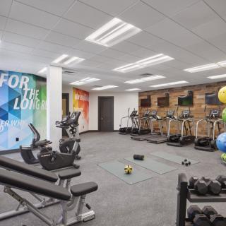 A modern gym featuring treadmills, dumbbells, and other exercise equipment in a spacious workout area.
