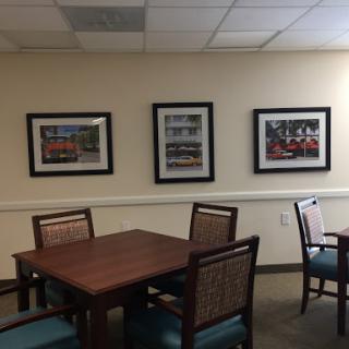 A cozy meeting room featuring a wooden table, chairs, and framed artwork on the walls.