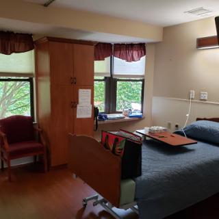 A comfortable hospital room with a patient bed, windows letting in natural light, and seating for visitors.