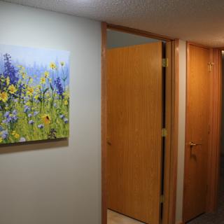 A hallway featuring closed wooden doors and a colorful floral painting on the wall.