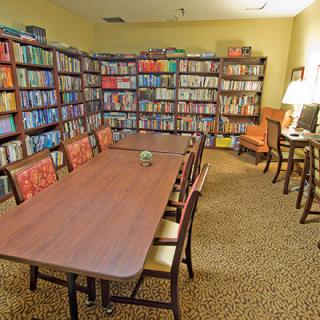 A cozy library reading room with a large table and bookshelves filled with books.