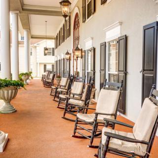 A picturesque porch lined with rocking chairs and elegant columns.
