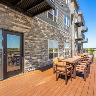 A stylish balcony with a wooden deck and outdoor dining furniture, perfect for gatherings.