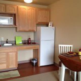 A small kitchen and dining area with basic appliances and wooden furniture.
