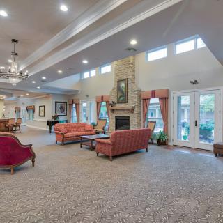 A spacious and elegantly decorated living room featuring comfortable sofas, a central fireplace, and large windows for natural light.
