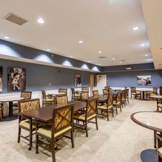 A spacious dining area with multiple tables and chairs, decorated with artwork on blue-painted walls.