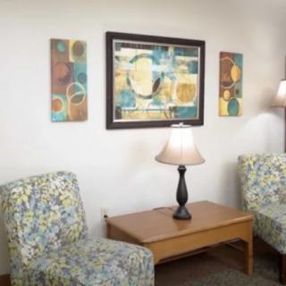 A cozy living room with patterned armchairs, a wooden coffee table, and abstract wall art.