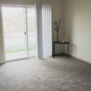 A minimalist empty room with a sliding glass door and carpeted floor.