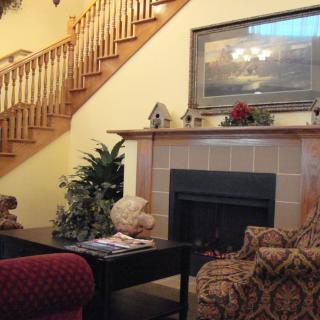A cozy living room with a fireplace, elegant staircase, and comfortable seating.