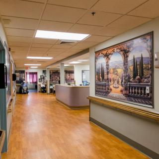 A hospital hallway featuring a large decorative painting on the wall.