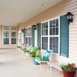 A cozy porch with benches and colorful plants.