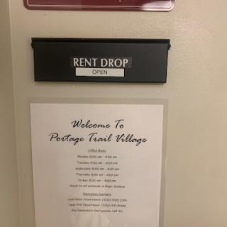 A rent drop box and informational sign welcoming residents to Portage Trail Village.