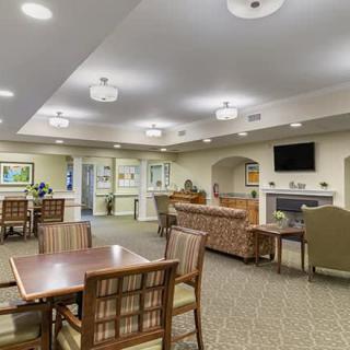 A well-furnished living area with tables, chairs, and a sofa in a comfortably lit setting.