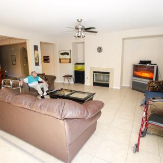A cozy living room with a brown leather sofa, television, and fireplace.
