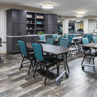 A spacious and well-lit dining or meeting area with multiple tables and chairs arranged, featuring modern interior design.