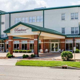 The entrance of a hotel with a landscaped exterior.