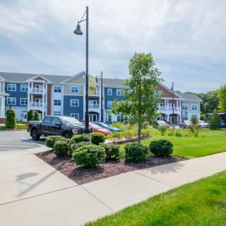 A well-maintained apartment complex with lush greenery and a parking area.
