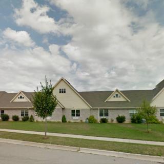 A suburban residential house with a lawn and cloudy sky.
