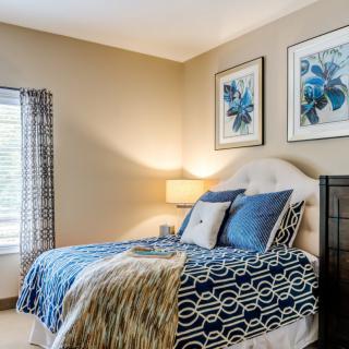 A cozy bedroom with modern decor featuring blue accents and framed artwork.