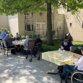 Seniors gathering outdoors for a social activity on a sunny day.