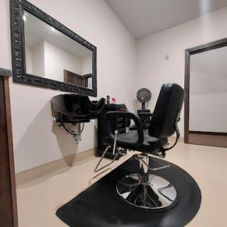 A stylist's workspace featuring a barber chair and large mirror, designed for beauty and grooming services.