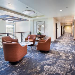 A modern lobby with a seating area featuring comfortable chairs and a patterned carpet.