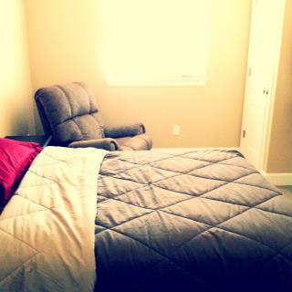 Cozy bedroom with a comfortable chair and neatly made bed.