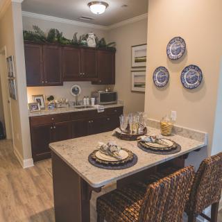 A cozy kitchen with a small dining area featuring bar stools and decorative plates on the wall.