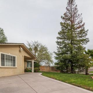 A suburban house with a spacious driveway and a well-maintained yard featuring tall trees.