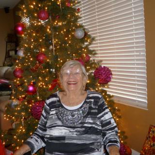 A person smiling in front of a decorated Christmas tree.