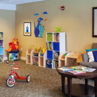 A cozy and inviting children's playroom filled with toys, a tricycle, bookshelves, and colorful decorations.