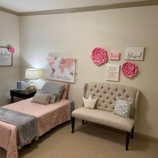 A cozy bedroom with pink accents and elegant wall art.