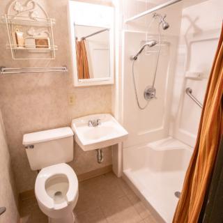 A compact bathroom featuring a toilet, sink, and shower.