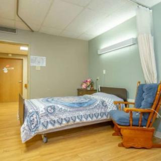A tidy hospital room featuring a bed and a rocking chair.