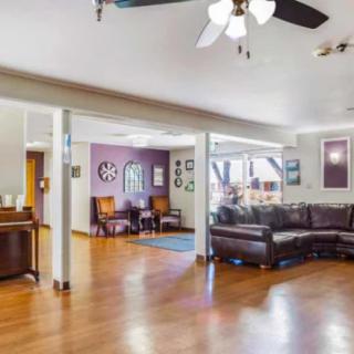 A spacious living room with hardwood floors, a ceiling fan, and comfortable seating.
