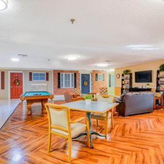 A spacious living room with vibrant colors, featuring a cozy seating area, entertainment setup, and a table with chairs.