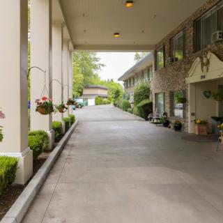 A view of a hotel entrance with a covered driveway and landscaped surroundings.