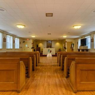 Interior view of a small chapel with wooden pews facing the altar.