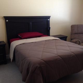 Cozy bedroom with a neatly made bed and an armchair.
