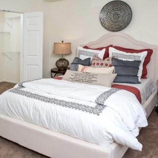 A cozy bedroom with a neatly made bed, featuring layered pillows and elegant decor.