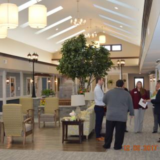 A spacious lobby area with people engaged in conversation, surrounded by comfortable furniture and decorative plants.