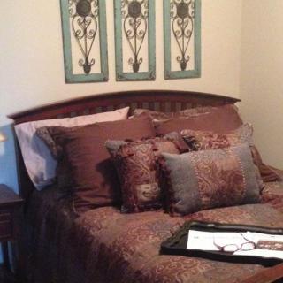 A cozy bedroom with decorative pillows and artwork.