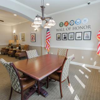 A well-appointed meeting room featuring a conference table, chairs, and patriotic decor, including American flags and a 'Hall of Honor' display with framed photos.