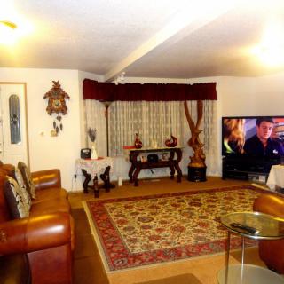A cozy living room with warm lighting, featuring a leather sofa, patterned rug, and a television.