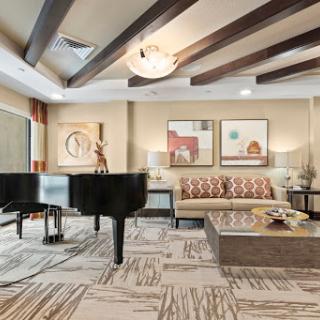A stylish living room featuring a grand piano, modern furniture, and artistic decor.