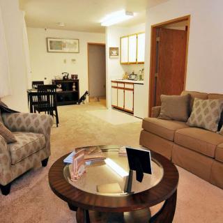 A cozy living room with comfortable seating and a small dining area in the background.
