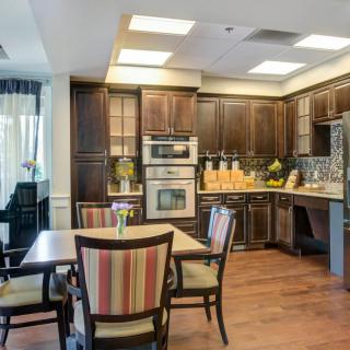 A modern kitchen and dining area featuring wood cabinets, contemporary appliances, and a small dining table with chairs.
