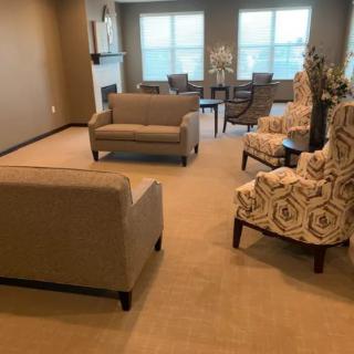 A cozy living room with sofas, patterned chairs, and a dining table by the windows.