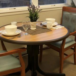 A small dining table set with cups and plates, adorned with a plant centerpiece.